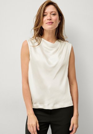 Cremefarvet ærmeløs bluse med draperet front, glat tekstur og rund udringning. Bæres med sorte bukser. Simpelt og elegant design.