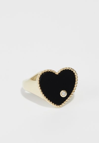 Goldfarbener herzförmiger Ring mit einem schwarzen Emaille-Mittelstück und einem kleinen klaren Stein. Der Rand ist mit einem gedrehten Seildesign verziert.
