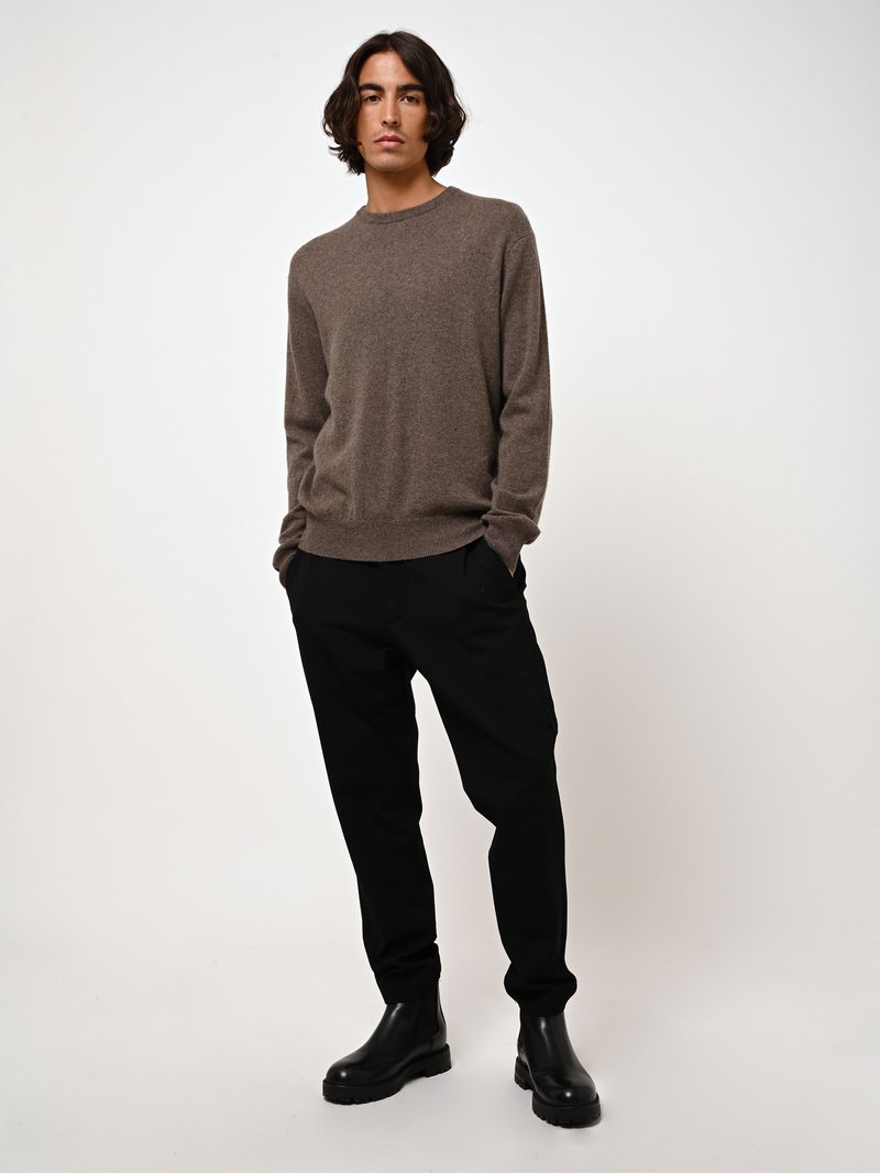 Bruine sweater van zacht materiaal, ronde hals, losse pasvorm. Gecombineerd met zwarte taps toelopende broek en stevige zwarte hakken.