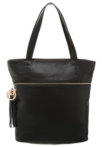 Sac fourre-tout en cuir noir avec une fermeture éclair sur le dessus, un fond plat, deux poignées et un ornement à pampilles avec un charm circulaire. Texture lisse, design simple.