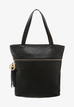 Czarna skórzana torba typu tote z górnym zamkiem błyskawicznym, płaską podstawą, dwoma uchwytami oraz ozdobą w postaci frędzla z okrągłym brelokiem. Gładka faktura, prosty design.