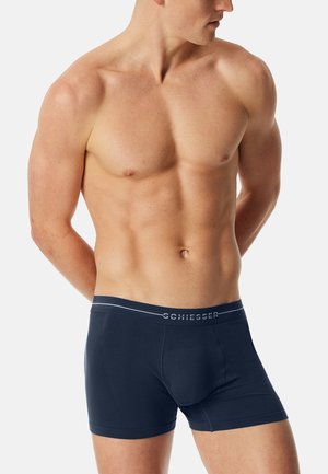 Marinblå boxershorts tillverkade av stretchigt tyg, med en slät midjeresår som har "SCHIESSER"-logotypen och ribbad struktur på sidorna.