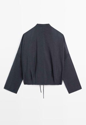 Ciemnoszara kurtka o luźnym kroju, z długimi rękawami, wysokim kołnierzem i ściągaczem u dołu, pokazana od tyłu na białym tle.