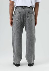 Loszittende grijze spijkerbroek van denim met een verweerde afwerking, twee achterzakken en een rechte pijpvorm. Kenmerkende hardware op de tailleband.