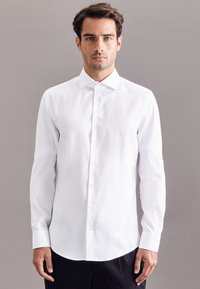 Witte lange mouwen blouse met een puntige kraag, knoopsluiting aan de voorkant en een gebogen onderrand; gladde textuur en getailleerd ontwerp.