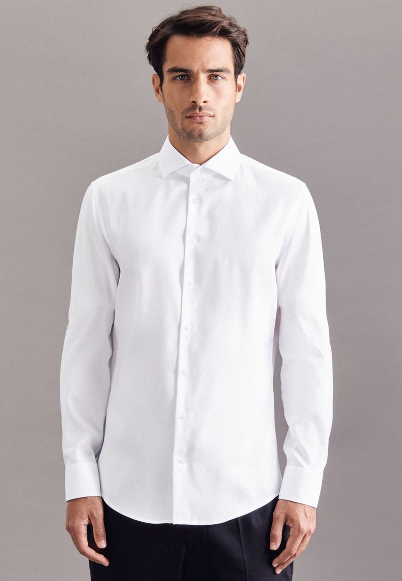 Witte lange mouwen blouse met een puntige kraag, knoopsluiting aan de voorkant en een gebogen onderrand; gladde textuur en getailleerd ontwerp.