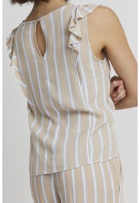 Top senza maniche beige con strisce verticali bianche e blu, con dettagli arricciati sulle spalle e chiusura a bottone sul collo posteriore.