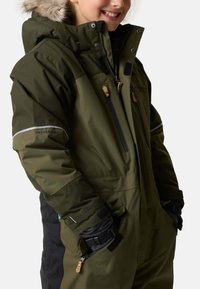 Green insulated ski jacket with fur-lined hood, multiple zippered pockets, elastic cuffs, and reflective accents. Fabric appears durable and weather-resistant.