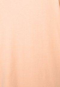 Lyserød peach t-shirt med en glat, blød bomuldsstruktur. Simpelt design uden mønstre eller accenter, med rund halsudskæring og korte ærmer.