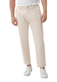 Beige geplooide broek met rechte pijpen, gemaakt van lichtgewicht stof, voorzien van een knoopsluiting en zijzakken, gecombineerd met witte sneakers.