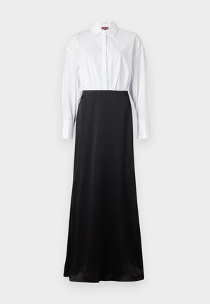 Chemise blanche à manches longues assortie à une jupe maxi en satin noir, créant un design stratifié en deux tons.