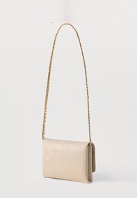 Μπεζ τσάντα ώμου από δερματίνη με υφή, με κλείσιμο με καπάκι και χρυσή αλυσίδα για λουρί, όρθια σε λευκό φόντο.