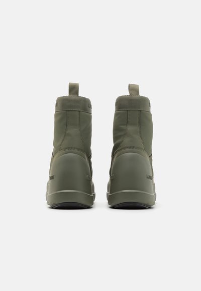 Bottes imperméables vertes avec une finition lisse et mate ; col haut ; accents élastiques ; et une languette à l'arrière pour un enfilage facile.