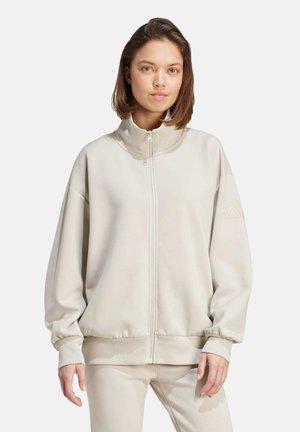 Helles beige Zip-Up-Sweatshirt mit hohem Kragen, lockerer Passform und gerippten Bündchen. Verfügt über ein dezentes Logo-Detail und eine glatte Textur.