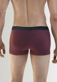 Bordowe slipki bokserskie wykonane z gładkiego materiału z czarnym pasem w talii z wytłoczonym logo. Dopasowany krój z krótką nogawką.