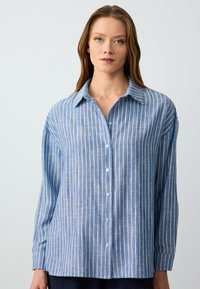 Blue striped button-up shirt made of lightweight fabric. Features a collar, long sleeves, and a relaxed fit with subtle vertical pattern.