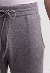 Graue Sweatpants aus einem weichen, strukturierten Stoff. Mit elastischem Bund und Kordelzug sowie Seitentaschen.
