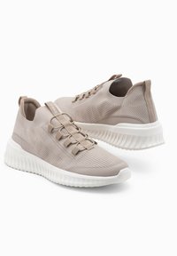 Sneakers in maglia beige con una tomaia testurizzata, chiusura con lacci e suola bianca rigata. Presentano un pull tab sul retro per una facile calzata.