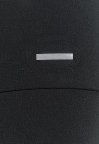 Svarta idrottsleggings med en slät textur och en reflekterande silverhorisontell accent på den nedre framsidan.