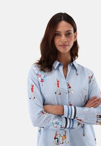 Light blue button-up shirt with colorful fashion-themed illustrations. Features striped cuffs and a soft, smooth texture.