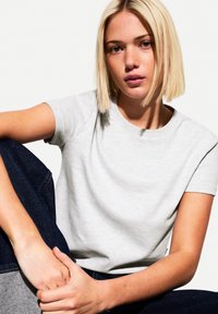 Light gray short-sleeve t-shirt with a crew neckline, made of soft cotton material. Relaxed fit, paired with dark blue jeans.
