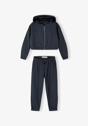 Hoodie bleu marine coupé, avec fermeture éclair à l'avant et deux poches, porté avec un pantalon de jogging assorti à taille élastique présentant des poches latérales et des chevilles côtelées.