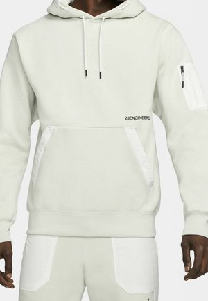 Lichtgrijze hoodie met een trekkoordcapuchon, een voorzak en een zijzak met rits. Heeft een gequiltte textuur op de accenten van de zakken en branding.