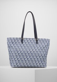 Námořnická taška přes rameno s bílým geometrickým vzorem, koženým lemováním a dvojitými ramenními popruhy. Pevný design a prostorný vnitřek.