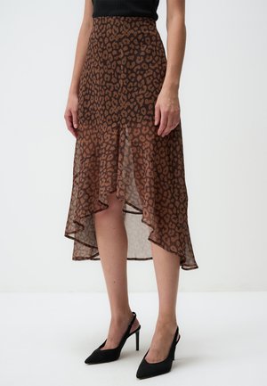 Jupe midi brune et transparente avec un imprimé léopard, l'ourlet plonge sur les côtés et la taille est ajustée. Associée à des talons noirs pointus.