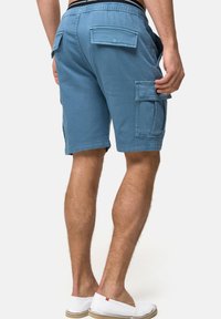 Un short cargo bleu à coupe décontractée, avec deux poches plaquées à l'arrière et sur le côté, fabriqué en coton léger.