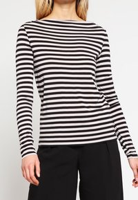 Długi rękaw, bluzka w czarno-białe poziome paski, wykonana z miękkiego materiału, z okrągłym dekoltem i dopasowaną sylwetką.