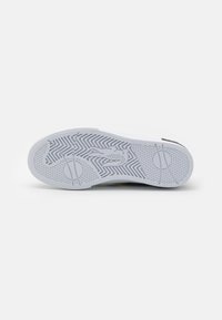 Suela de zapatilla blanca con un patrón de espiga, acentos circulares y áreas de agarre texturizadas. Acabado suave con un tono gris claro.