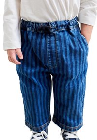 Blå randiga jeansbyxor med avslappnad passform, elastisk midja och sidofickor. Matchas med vit långärmad tröja och blå sneakers.