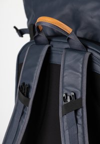 Zaino navy con un esterno liscio, spallacci imbottiti e regolabili, dettaglio in pelle e accessori neri per chiusure sicure.
