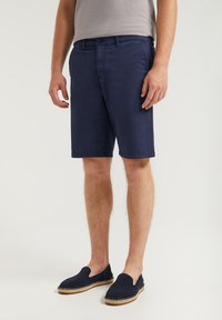 Marina bomullsbyxor med en figursydd design och sidofickor, tillsammans med marina slip-on skor med jutesula. Strukturerad tyg.