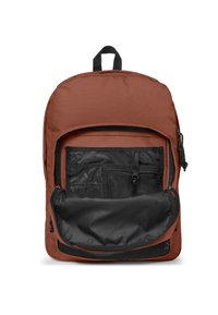Brązowy plecak z tkaniny z czarną kieszenią na zamek z przodu i dużym otworem. Posiada siateczkowe przegrody oraz pętlę do przenoszenia na górze.