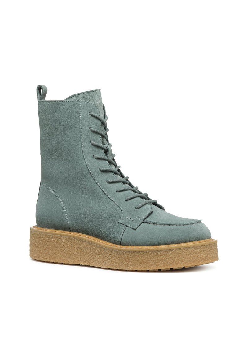 Bottine à lacets en suede bleu clair doux, avec un bout rond et une semelle compensée beige épaisse et texturée. Présente un tirant à l'arrière.