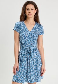 Vestido floral azul con mangas cortas, escote en V, cintura ceñida y falda acampanada. Presenta un patrón floral blanco y un detalle de lazo en la cintura.