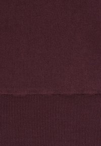 Tissu tricoté violet foncé avec une texture lisse, passant à un motif côtelé en bas. Répartition homogène de la couleur sur toute la surface.