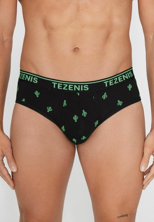 Torse masculin portant un slip noir avec des imprimés cactus verts et une taille noire avec un logo "TEZENIS" vert, se tenant devant un fond uni.