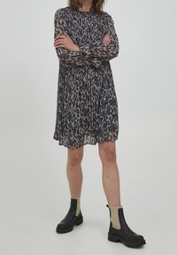 Leopardmönstrad klänning med långa ärmar, veckad design och hög halsringning. Matchad med svarta ankelboots med beige detaljer.