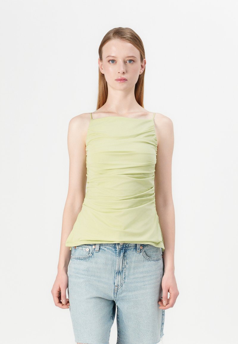 Lichtgroene, getailleerde tanktop met gerimpelde textuur en dunne bandjes, gecombineerd met hoogontwikkelde denimshorts. Eenvoudig en strak ontwerp.