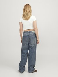 Vide ben blå denim jeans med høj talje, fem lommer og subtile slidmærker. Bæres med en tætsiddende hvid crop top.