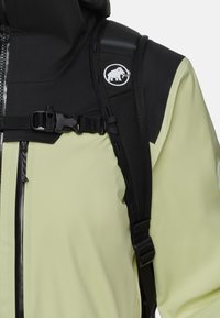 Wasserabweisende Jacke in hellgelb mit schwarzen Akzenten. Verfügt über eine Reißverschlusstasche, verstellbare Träger und ein Logo-Patch auf der Schulter.