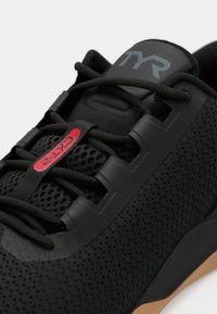 Black athletic shoe with mesh upper, rubber sole, and cushioned insole. Features round laces and prominent red and grey branding accents.