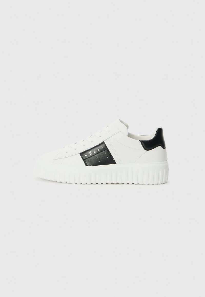 White sneakers with black accents, featuring a textured side panel, flat laces, and a chunky white outsole for added grip.