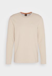 Chemise beige à manches longues en maille côtelée, col rond, avec un logo "BOSS" en relief subtil sur la poitrine et un col intérieur bordé d'orange.