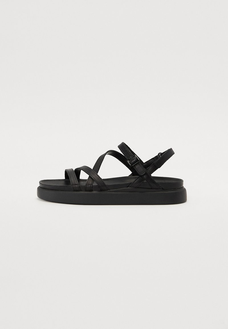 Zwarte sandalen met meerdere kruisbanden en een verstelbare enkelband. De zool is plat en gemaakt van een gestructureerd materiaal.