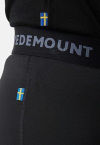 Black athletic pants feature a wide elastic waistband with "VEDEMOUNT" text and small Swedish flag accents on both the waistband and side.