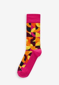 Chaussettes multicolores présentant un motif géométrique en rose, orange, noir et jaune. Fabriquées en matériau doux, avec un bord côtelé rose.